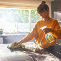 Woman using ECOS all-purpose to clean her bright, well-lit kitchen. ECOS cleaning products are sustainable and good for the home.