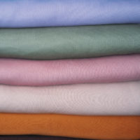 Stack of Pastel natural color Fabrics on white background. Fabrics And Clothing Arranged In Neat Stacks. Fabrics pile background.